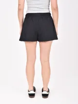 Short negro de tela de buzo, con cintura elástica ajustable con cordón y bolsillos laterales. El ruedo tiene una abertura lateral.