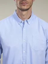 Camisa celeste de manga larga con cuello abotonado y bolsillo en el pecho.