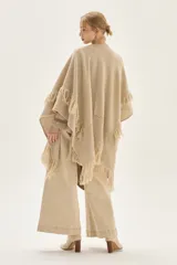 Ruana tejida en lana de cordero con diseño de sectores calados y terminación con flecos en los bordes.