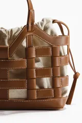 Bolso tote marrón estructurado con armazón exterior de cuero sintético entrelazado e interior de lona de lino y algodón con cordones ajustables.