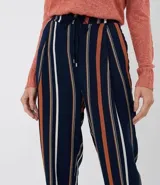 Pantalón de viscosa con rayas verticales en azul marino, blanco y naranja. Tiene bolsillos laterales, cintura elástica con cordón ajustable y tobillos ajustados con elástico.