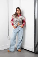 Saco de punto con diseño combinado, presenta un estampado animal print en el cuerpo y mangas con rayas horizontales en rojo y beige. Posee cuello redondo, cierre frontal con botones y terminaciones en tejido acanalado rojo.