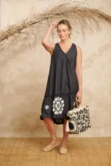 Vestido negro con escote en V, corte holgado, largo midi y volado bordado en el ruedo.