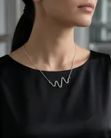 Collar de plata 925 con cadena fina y dije central con diseño abstracto de serpiente.