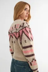 Saco tejido con diseño geométrico estilo inca, en tonos beige, rosa y marrón. Presenta cuello redondo, cierre frontal con botones y puños acanalados.