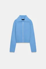 Chaqueta de punto color azul, con cuello solapa, manga larga y cierre frontal con cremallera. Presenta acabados en rib en puños y ruedo.