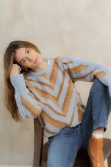 Sweater de punto jacquard con diseño de chevron en tonos celeste y marrón. Presenta cuello redondo, corte holgado y mangas largas con hombros abullonados.