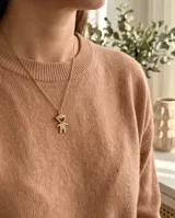 Collar de bronce dorado con cadena fina y dije en forma de silueta de niño adornado con circónias.