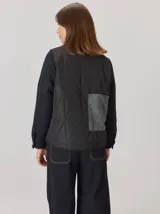 Campera de diseño híbrido con frente acolchado en color tostado, solapas y cuello en tejido de lana con patrón de cuadros tipo príncipe de gales, y mangas en paño de lana color azul marino. Cuenta con cierre frontal de botones.