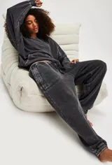 Pantalón de jogging negro con efecto gastado (acid wash), tiro medio y silueta relajada con puños ajustados en los tobillos. Presenta cordón de ajuste en la cintura y costuras visibles en contraste.