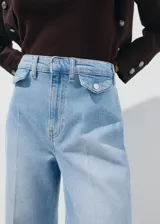 Pantalón de jean de tiro medio y diseño wide leg con bolsillos de solapa delanteros, trabillas para cinto y cierre con gancho y cremallera.