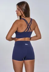 Conjunto deportivo compuesto por un top de escote redondo con banda elástica inferior y logo estampado, y un short de tiro alto ajustado. Ambas piezas son de color azul marino.