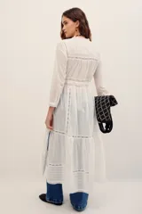 Camisa larga blanca de algodón estilo túnica, con detalles de encaje y bordados en el frente y mangas largas.