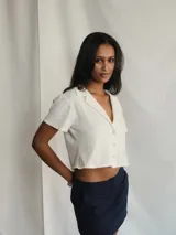 Top de manga corta color gris oscuro con cuello tipo solapa y cierre frontal de botones.