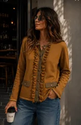 Chaqueta de punto color mostaza con detalles en verde oliva, presenta volados frontales a lo largo de la botonadura, bolsillos con solapa y cierre frontal con botones.