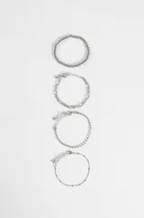 Set de cuatro pulseras de cadena en tono plateado con diferentes diseños, incluyendo una de esferas pequeñas, una de eslabones tipo figaro, una de cadena fina con pequeñas cuentas y una cadena delgada con detalles espaciados.