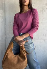 Remera de manga larga color rosa, con cuello redondo y detalle de bordado floral en el hombro izquierdo.