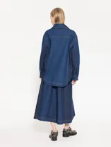 Camisa de denim azul con costadillos y bajo mangas en denim azul marino, punteras metálicas níquel en puntas de cuello, broches semi esfera níquel en centro delantero y puños, bordado JCH de hilo a contra tono en ruedo del lado derecho.