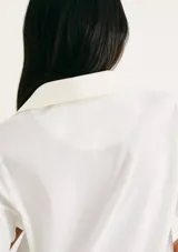 Camiseta blanca de manga corta con cuello polo profundo en V y logo bordado de Hering en el pecho.