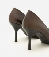 Zapato tipo scarpin de color marrón oscuro, confeccionado en poliuretano con acabado liso. Presenta un diseño clásico con punta fina y taco fino de altura media.