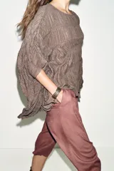 Top de cuello redondo color celeste con textura fruncida, mangas tipo capa y bajo asimétrico.