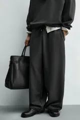 Pantalón de corte baggy fit confeccionado en tejido técnico, con cintura elástica ajustable mediante cordón y bajo con elásticos laterales para ajuste.