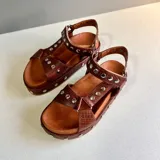 Sandalias marrones de cuero con suela de plataforma y detalles de tachas plateadas.