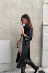 Tapado largo de cuero negro con cuello desmontable y detalles en peltre en las mangas. El cuello desmontable es reversible, de un lado peltre y del otro marrón.