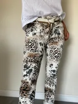 Pantalón de mujer con estampado animal print en tonos marrones y negros, de corte ajustado y largo hasta el tobillo. Incluye un cinturón de tela a rayas blancas y marrones.