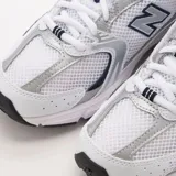 Championes New Balance modelo 530 de estilo retro para running, confeccionados en malla blanca con superposiciones plateadas y azul marino. Cuentan con amortiguación ABZORB en la suela y el característico logotipo "N" en los laterales.