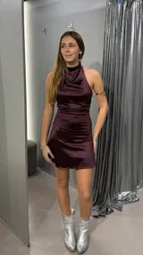 Vestido corto de satén color bordó, con cuello alto drapeado y espalda descubierta. Presenta un ajuste entallado que resalta la silueta.