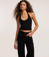 Pantalón de sarga color negro con corte recto estilo años 90, de cintura alta y piernas sueltas. Presenta aplicaciones de strass en toda la parte frontal, cierre con botón y cremallera, y bolsillos funcionales.