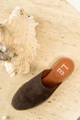 Mules de cuero negro con tachas plateadas en el borde de la suela y plantilla con logo estampado.