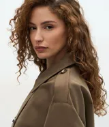 Trench coat corto de la marca Cortelle, confeccionado en una mezcla de algodón y poliéster. Presenta un diseño estructurado con cierre cruzado de botones, cuello clásico, mangas largas con trabillas en los puños y bolsillos frontales.