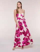 Vestido maxi de fondo blanco con estampado de flores grandes en tonos verde y marrón, con escote en V, breteles finos y detalle de abertura cut-out en el centro del busto.