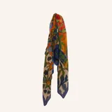 Pashmina con estampado multicolor de inspiración artística y floral, con predominio de tonos azules, rojos y amarillos, y bordes en azul marino.