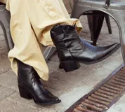 Bota tipo texana de caña corta, confeccionada en cuero con forro interior de cuero. Presenta un diseño clásico con costuras decorativas en la puntera y taco cuadrado de 4 cm. Incluye cierre lateral para facilitar su colocación.