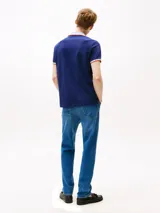 Chomba azul marino de algodón elástico, con cuello tejido a contraste en blanco y gris con ribete naranja. Tiene tapeta de dos botones, mangas cortas con ribete a contraste y logo de Tommy Hilfiger bordado en el pecho.