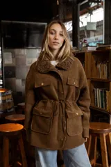 Campera de efecto gamuza color tostado con interior de corderito sintético. Presenta cierre frontal, bolsillos delanteros con solapa, cintura ajustable con cordón y puños con detalle de corderito.