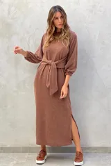 Vestido midi color marrón, de manga larga abullonada con puños elásticos, cuello redondo y lazo ajustable en la cintura. Presenta una abertura lateral en la falda.
