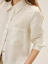 Camisa de lino color crudo con bolsillos frontales con solapa, cuello camisero, mangas largas y pespuntes en contraste.