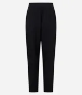 Pantalón de vestir negro, corte carrot (holgado en caderas y ajustado en tobillos), con talle alto, pliegues frontales y cierre tradicional con botón forrado.