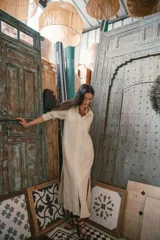 Camisa larga negra de manga larga, con cuello en V y ribete blanco contrastante a lo largo del frente y puños. Presenta aberturas laterales altas.