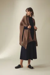 Ruana tejida en punto texturizado color marrón chocolate, con terminación de flecos en los bordes. Diseño inspirado en la vestimenta tradicional uruguaya, confeccionada en una mezcla de fibras suaves y ligeras.