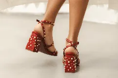 Sandalias de taco ancho con tachas doradas y plateadas distribuidas en las tiras y en el taco, de diseño con tiras cruzadas y cierre de hebilla en el tobillo.