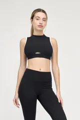 Top deportivo negro con escote alto, abertura en el centro del pecho y ribete blanco en sisas y cuello.