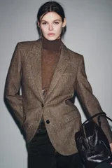 Blazer de Zara confeccionado en hilatura con lana, con diseño de espiga en tonos marrones. Presenta cuello solapa, manga larga con botones, bolsillo de vivo en el pecho y bolsillos delanteros con solapa. Cierre frontal con botones y forro interior negro.