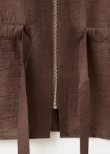 Blusa de mezcla de lino y viscosa color marrón, con diseño recto, cuello camisero, manga tres cuartos, bolsillo parche delantero, cierre de cremallera frontal y lazo ajustable en la cintura.