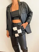 Blazer negro de cuerina con solapas, bolsillos frontales y corte holgado.