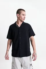 Camisa negra de manga corta con cuello cubano, corte recto y logo bordado en el pecho.